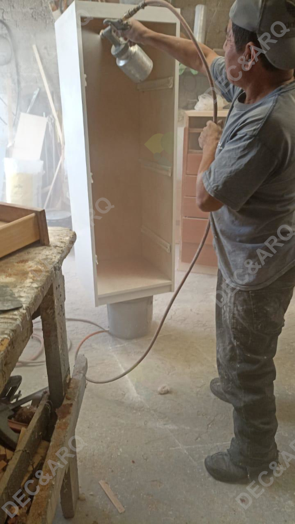 Hombre barnizando con pistola un mueble